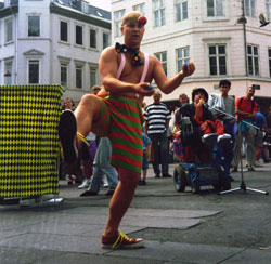 The busker Pino is juggling in front of the ringmaster and the cages with the monsters